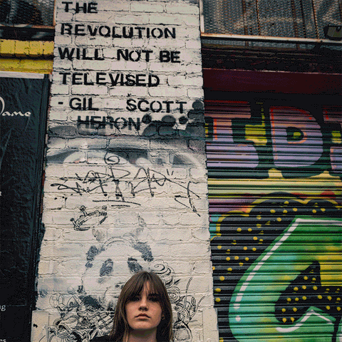 Person wearing a t-shirt with an upside-down American flag design that says America is Revolting
