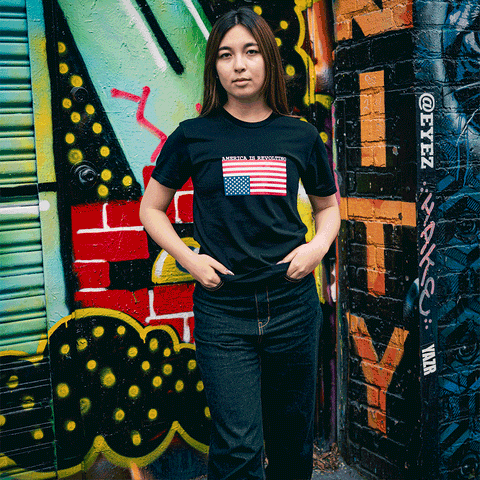 Person wearing a t-shirt with an upside-down American flag design that says America is Revolting