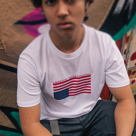 Person wearing a t-shirt with an upside-down American flag design that says America is Revolting