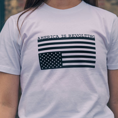 White t-shirt with American flag graphic upside down and 'AMERICA IS REVOLTING' text 