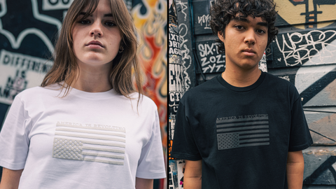 Woman in white t-shirt with an off-white print and man in black t-shirt with an off-black print where both shirts have an American flag graphic upside down and 'AMERICA IS REVOLTING' text 